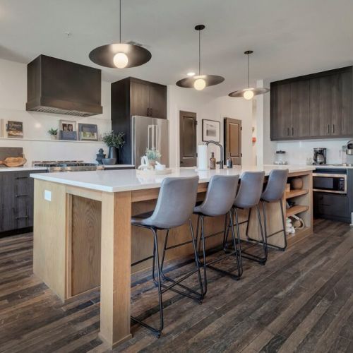 Modern kitchen island w/ bar seating, sleek cabinetry & pendant lights