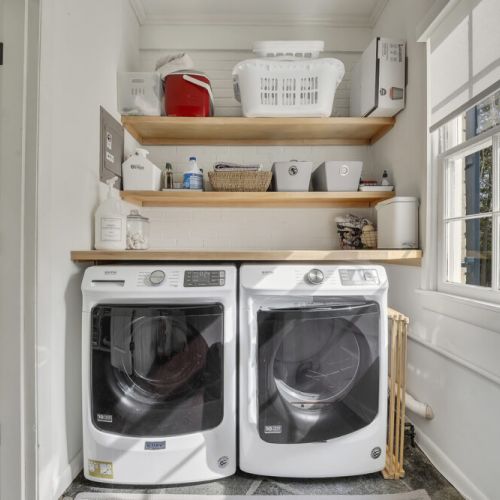 Dedicated laundry nook w/ washer, dryer & open shelving for easy organization