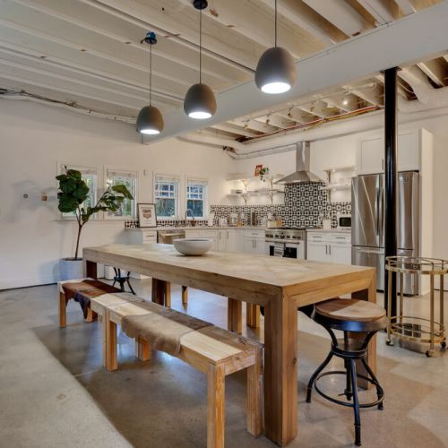 A unique basement kitchen and dining area featuring a massive natural wood dining table with benches
