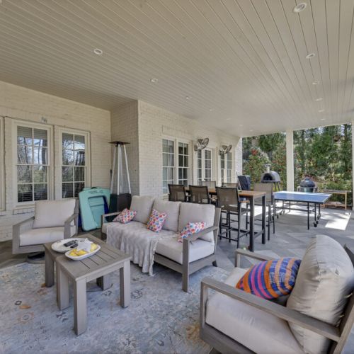 Covered patio w/ cushioned seating, a shaded space to relax & chat