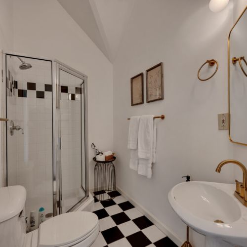 A bright, vintage-inspired bathroom featuring bold black and white checkerboard flooring