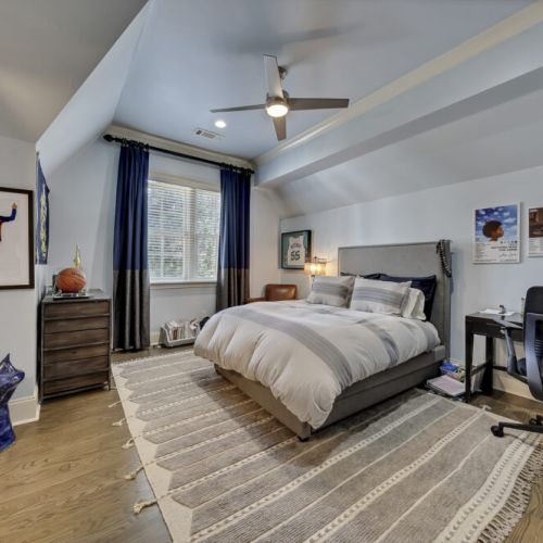 Cozy bedroom w/ soft bedding, warm tones & a ceiling fan for added comfort