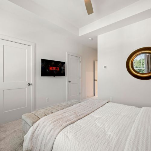 Bedroom 1 - A comfortable bedroom with bench seating and a wall-mounted Smart TV for relaxing in bed. Soft carpeting and neutral tones create a cozy retreat.