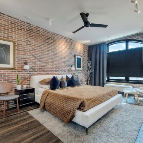 Minimal bedroom w/ brick wall, arched window & sleek TV setup