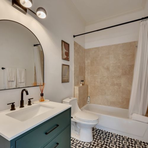 A stylish modern bathroom featuring a deep teal vanity,