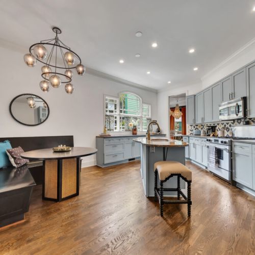 A sophisticated kitchen and breakfast nook featuring light gray-blue cabinets