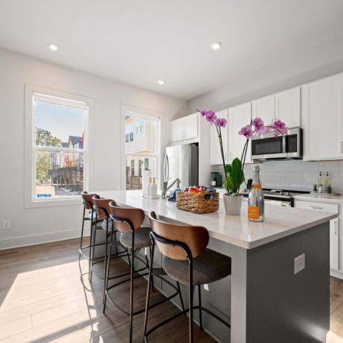Sun-filled kitchen with a spacious island and four comfortable bar stools. Large windows bring in natural light while providing a pleasant view of the surrounding neighborhood.