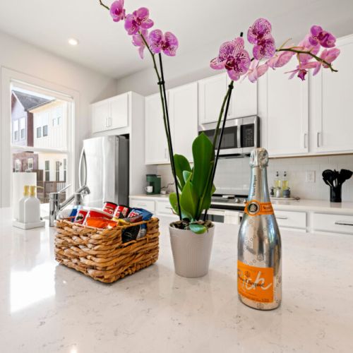 Bright kitchen featuring a spacious quartz island, breakfast bar seating, stainless-steel appliances, and a Keurig coffee maker—ideal for preparing meals and enjoying coffee together.
