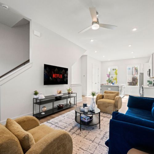Open-concept living room flows seamlessly into the fully equipped kitchen with white cabinetry, stainless steel appliances, and a kitchen island with seating for casual meals or conversation.