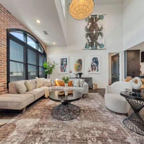 Bright double-height living room w/ arched windows, fireplace & cozy seating area