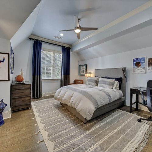 Cozy bedroom w/ soft bedding, warm tones & a ceiling fan for added comfort