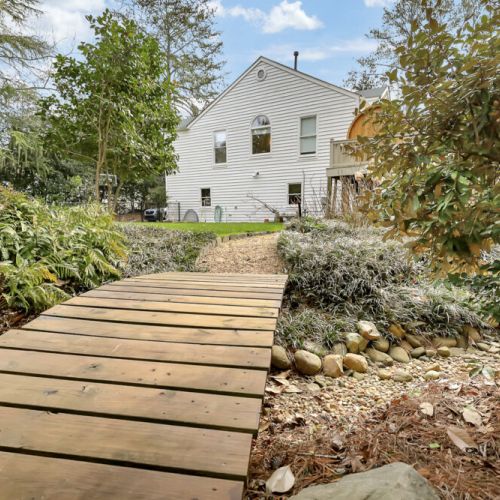 Wooden footbridge over a landscaped creek bed adds charm to the approach
