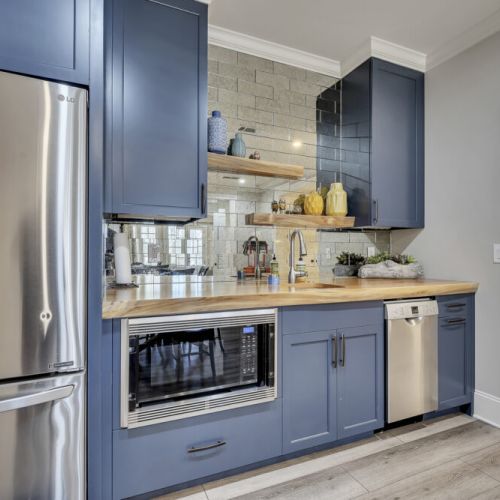 Stylish lower kitchen w/ blue cabinetry & stainless appliances for easy cooking