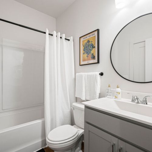 Bathroom 2 - Sparkling bathroom with a tub/shower combination, vanity, large round mirror, and complimentary toiletries. The clean, bright design provides a comfortable space to freshen up.