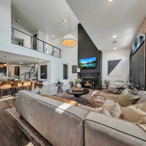 Open-concept living space showcasing a spacious seating area, fireplace, dining area, and kitchen, creating an ideal setting for gathering and entertaining.