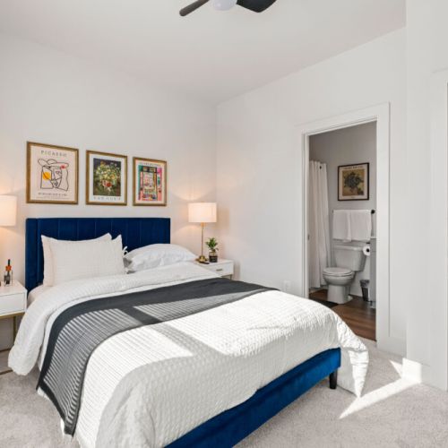 Bedroom 2 - Queen-size bed, bedside tables and lamps, and direct bathroom access. Large windows provide natural light, while the ceiling fan adds extra comfort.
