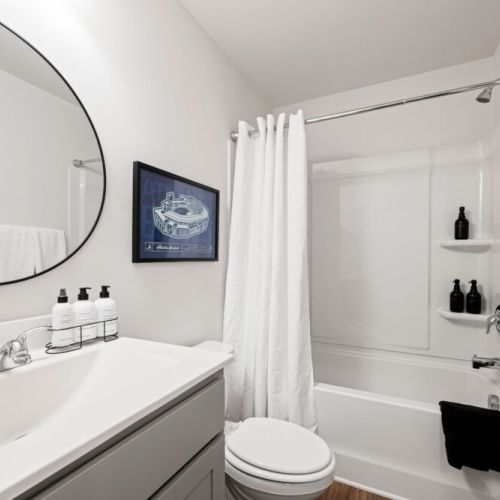 Bathroom 1 - Bathroom with a tub/shower combination, spacious vanity, large round mirror, and complimentary bath products for a comfortable and convenient stay.