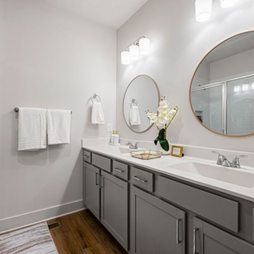 Full Bathroom 1 - Sparkling bathroom with a double vanity, two sinks, large round mirrors, and a glass-enclosed walk-in shower. Fresh towels and toiletries are provided for added convenience.