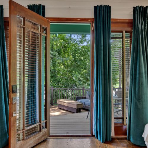 A large wood-framed French door is swung open in the center