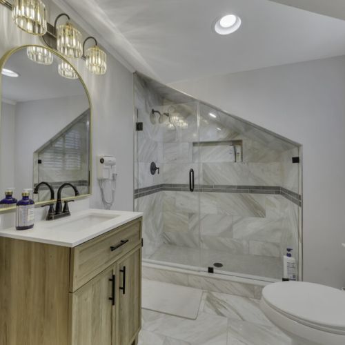 Backlit arched mirror and stylish triple-bulb light fixture