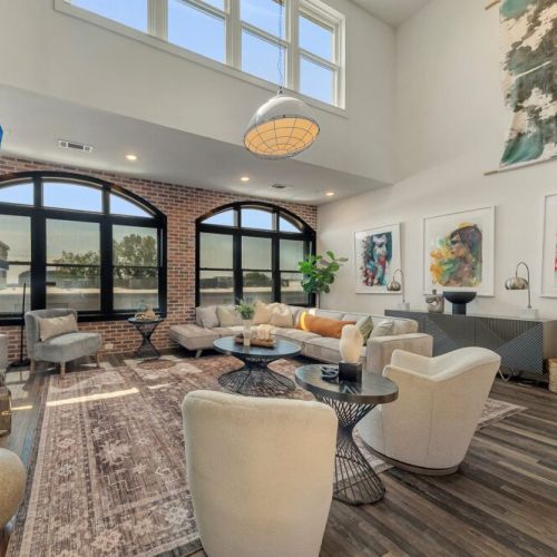 Inviting living area featuring a warm fireplace, plush seating, statement artwork, and expansive arched windows.
