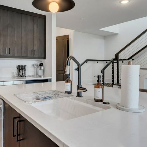 Expansive kitchen island beside staircase, perfect for cooking & gathering